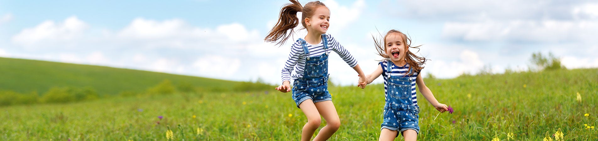 two young girls running in a field